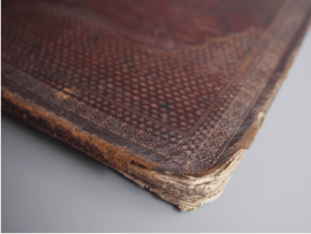 Before treatment - the damage to the edges of the leather bound board shows the layers coming apart beneath.