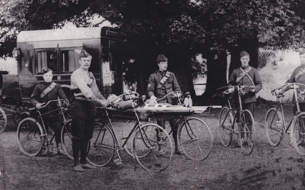 A demonstration of a bicycle litter, with a horse-drawn ambulance in the background, c. 1900 (Archive ref: PHO4732) 